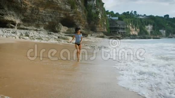 巴厘岛海滩布鲁内特的微笑穿过海滩上的沙子在水中冷却你的脚女人享受着视频的预览图
