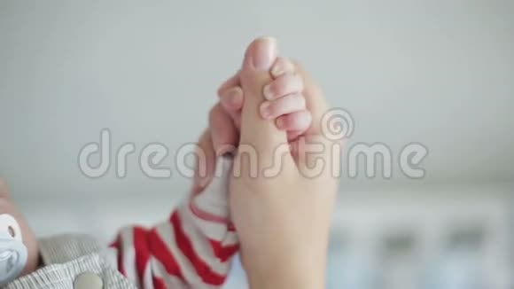 一个困倦的小男孩用奶嘴握住一只雌性的手视频的预览图
