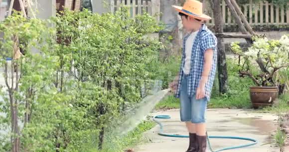 年轻的亚裔泰国男孩在花园的黑土上用小苗浇水视频的预览图