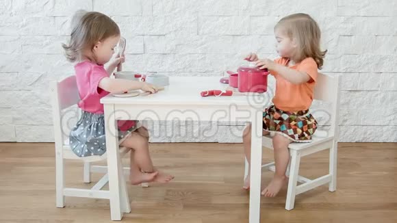 女孩们在白色的桌子上玩视频的预览图