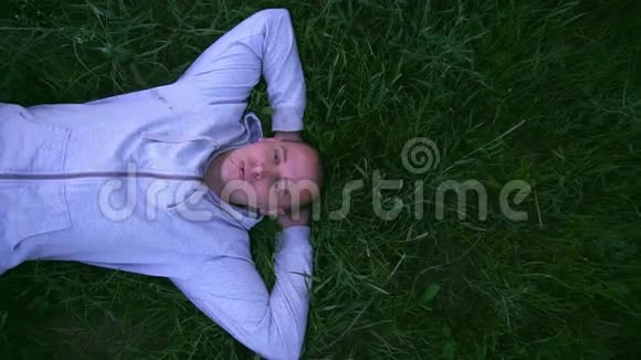 美丽的人躺在草地上嘴里衔着一根草慢动作视频的预览图
