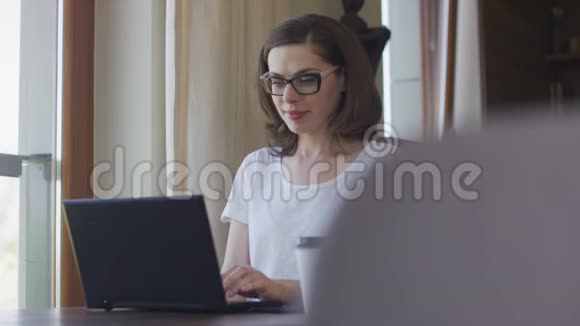 有魅力的女性在家使用智能手机和笔记本电脑视频的预览图