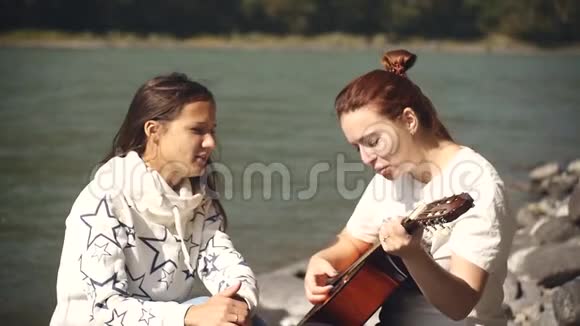 两个女朋友在河岸上休息唱歌弹吉他视频的预览图