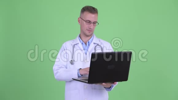 快乐的帅哥医生想着笔记本电脑视频的预览图