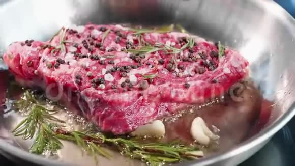 肉牛排加调味料和香草在煎锅上嘶嘶作响特写视频的预览图