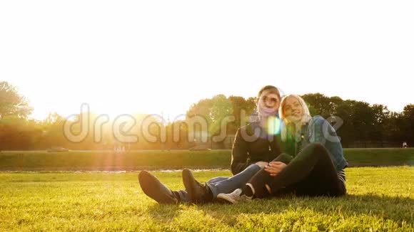 恋爱中的情侣坐在夏日公园的草地上视频的预览图