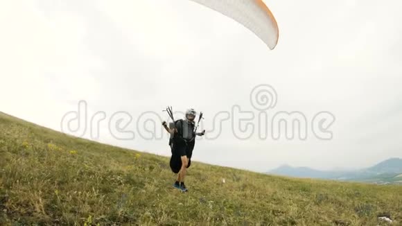 中镜头专业滑翔伞飞行员准备起飞抬起机翼沿着机翼抬起行走视频的预览图