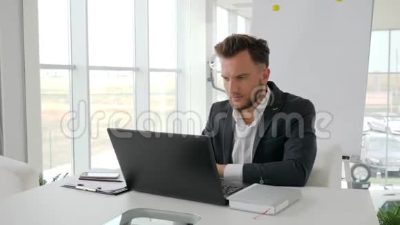 现代办公室年轻老板的电话交谈成功的商人在互联网上的笔记本电脑上工作视频的预览图