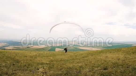 中镜头专业滑翔伞飞行员准备起飞抬起机翼沿着机翼抬起行走视频的预览图