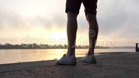 年轻人在缓慢运动的灿烂日落中在一个风景如画的河岸上跳跃视频的预览图