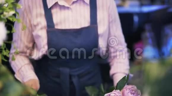 靠近一个女人花店做一束紫色的花向下倾斜视频的预览图
