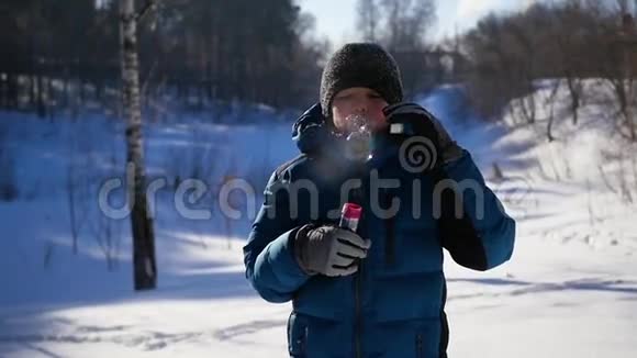 在一个阳光明媚的冬天男孩高兴地在公园里吹肥皂泡视频的预览图