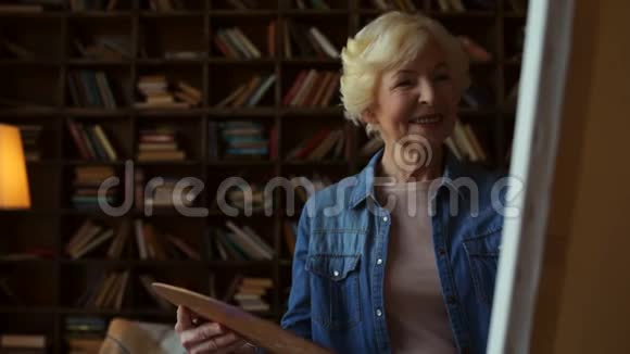漂亮的老妇人在家画画视频的预览图