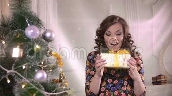 带圣诞礼盒的美女年轻可爱的女人很高兴得到礼物视频的预览图