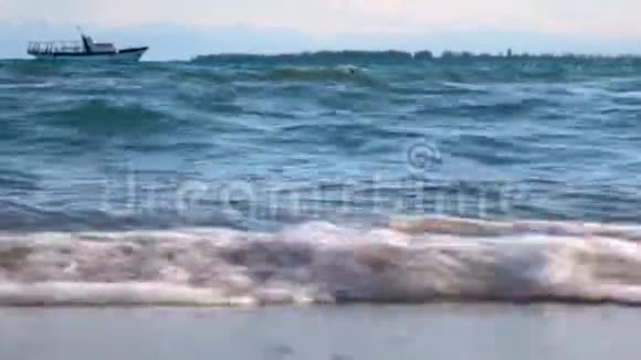 海滩上的海浪靠近地平线上有一艘船在游泳视频的预览图