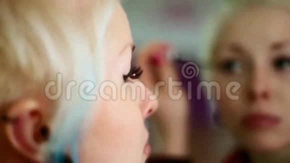 少女化了妆站在镜子前特写镜头视频的预览图