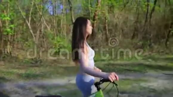 年轻的混血女子骑自行车骑着山地车在森林里散步疲惫的自行车锻炼户外视频的预览图