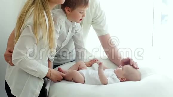 父母和父母亲吻躺在床上的新生儿视频的预览图