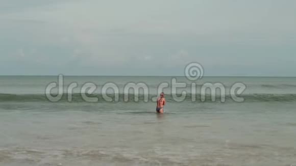 穿着比基尼在海浪中的年轻女性享受日光浴和海滩度假视频的预览图