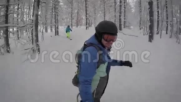 成年男性有红色的胡须被霜冻覆盖在一个黑色的滑雪板上骑在冬林里在他身后视频的预览图