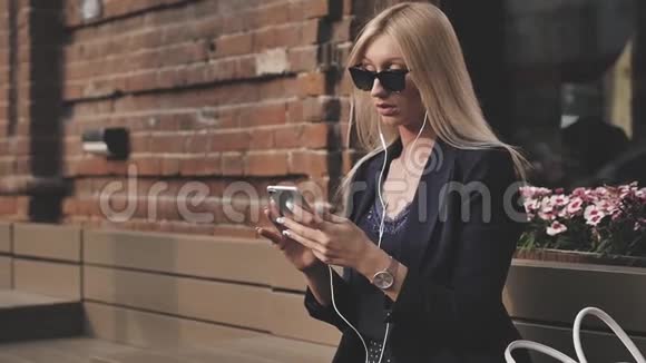 穿西装的年轻商务女性在智能手机上写信息一个漂亮的金发女郎正坐在长凳上用一个视频的预览图