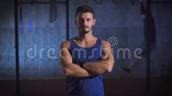 强壮的男人穿着蓝色衬衫手臂交叉在健身房摆姿势视频的预览图