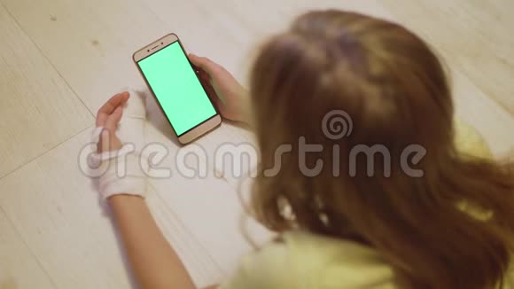 年轻的白种人金发左手骨折看着智能手机的绿色屏幕近距离观看视频的预览图