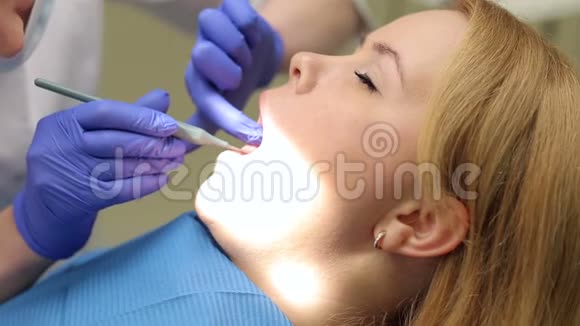 一位女牙医用镜子检查牙齿视频的预览图