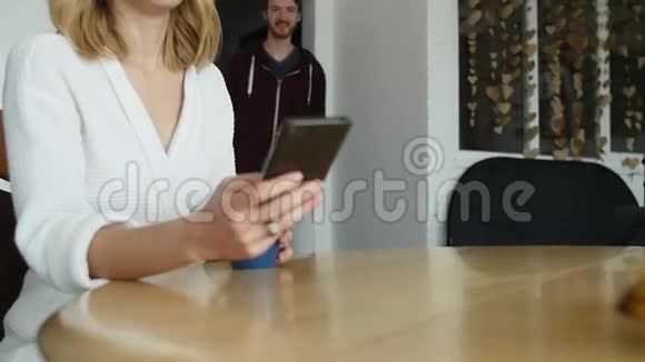 漂亮的女人坐在厨房里上网吃早餐视频的预览图