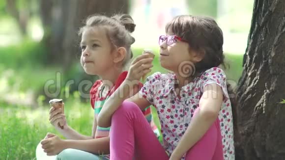 儿童坐在公园草地上的特写肖像女朋友吃冰淇淋玩得开心视频的预览图