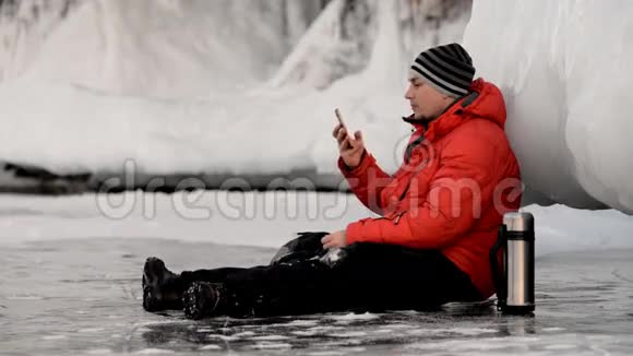 那个人正在冰岩边使用智能手机视频的预览图