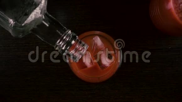 酒保把伏特加从一个瓶子里倒入一个杯子里上面有果汁慢动作视频的预览图