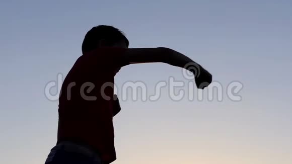 小男孩在秋天的日落时在湖岸上打拳视频的预览图