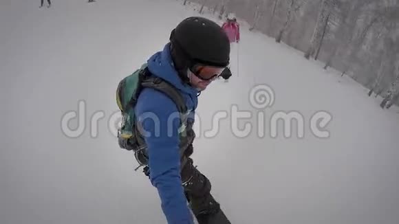 运动男热情地穿着运动装备迅速地滚下斜坡在下雪的天气里做小把戏是的视频的预览图