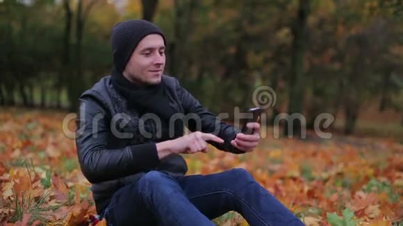 男子度假智能手机和开始有一个视频游戏而坐在公园视频的预览图
