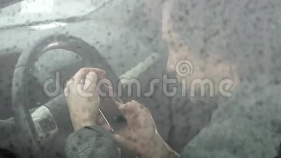 男人在车里用手机模糊了路上大雨的形象视频的预览图
