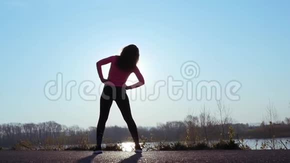 运动的女人在日出时在河岸上参加运动慢动作视频的预览图