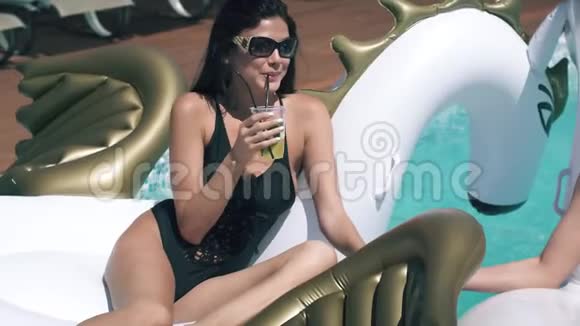 女孩们在海滩上喝着清爽的鸡尾酒女朋友在充气床垫上晒日光浴和游泳视频的预览图