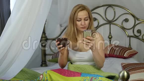 快乐的女人坐在床上跳舞唱歌喝咖啡和朋友在电话里聊天视频的预览图