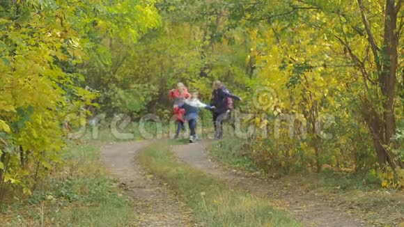 快乐的孩子们跑过秋天的公园把背包扔起来抓住他们慢动作有趣的情绪视频的预览图