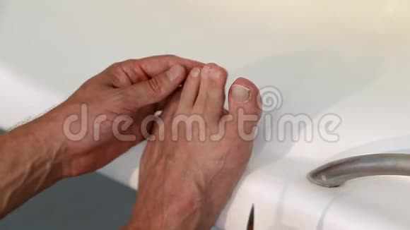 男人在浴室用剪刀剪脚趾甲白人男子用脚修剪脚趾甲特写镜头视频的预览图