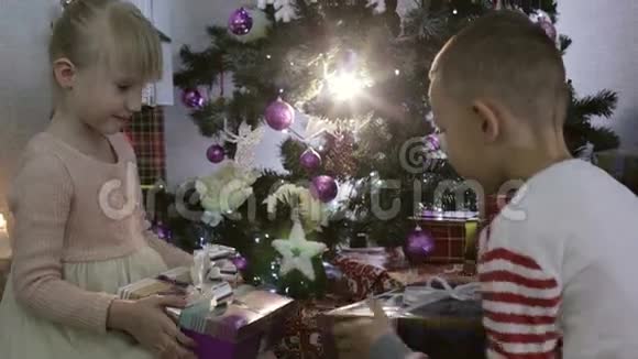 男孩和女孩在圣诞树附近互相送礼物视频的预览图