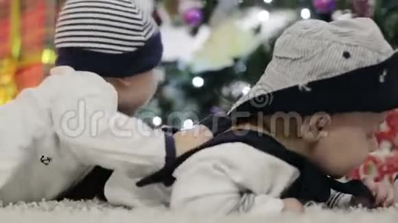 两个穿着水手装的婴儿趴在肚子上在圣诞树附近爬行视频的预览图