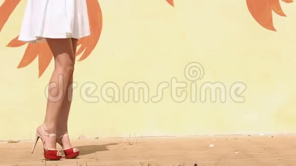 穿高跟鞋的女人在黄色墙壁附近行走特写镜头视频的预览图