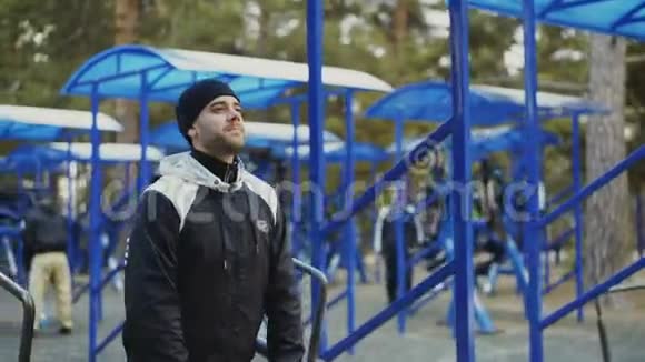肌肉男在冬季公园的户外健身房锻炼视频的预览图