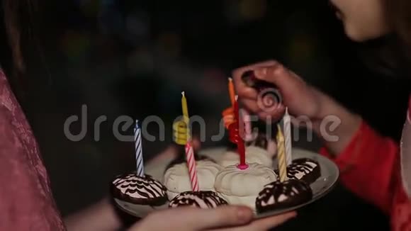 两个十几岁的女孩在生日时点燃蜡烛蛋糕加蜡烛特写视频的预览图