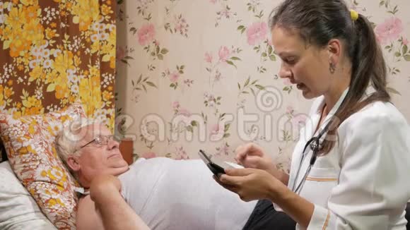 一位女医生在家审问一位病人她在平板电脑上写了一篇文章视频的预览图