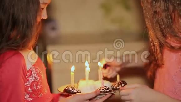两个十几岁的女孩在生日时点燃蜡烛蛋糕加蜡烛特写视频的预览图
