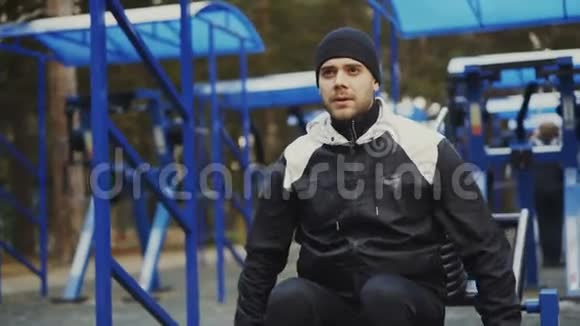 肌肉男在冬季公园的户外健身房锻炼视频的预览图