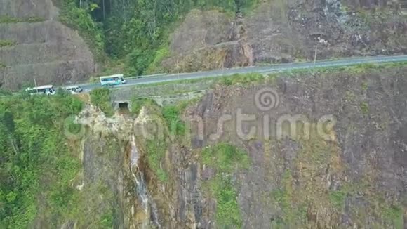 Flycam展示巴士在悬崖上的路上有美丽的瀑布视频的预览图